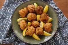 a bowl filled with tater tots and lemon wedges on top of a table