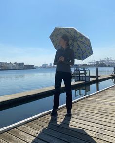 a woman standing on a dock holding an umbrella