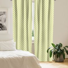 a bedroom with green polka dot curtains and white bedding