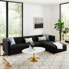 a living room with black couches and white rugs on the hardwood flooring