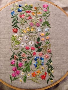 a close up of a embroidery on a piece of cloth with flowers in the middle