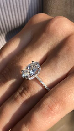 a woman's hand with a diamond ring on top of her finger and an engagement band