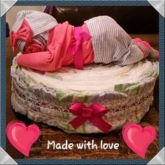 a baby is laying on top of a diaper cake with pink hearts around it