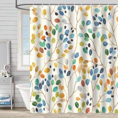 a shower curtain with colorful leaves on it in a white bathroom, next to a bathtub