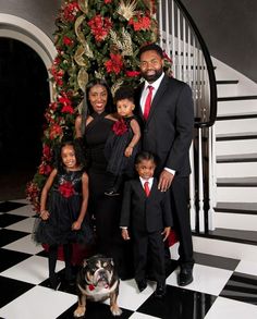 a family posing for a photo in front of a christmas tree with a dog on the floor