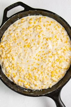 a skillet filled with corn on top of a table