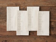 four white napkins on top of a wooden table