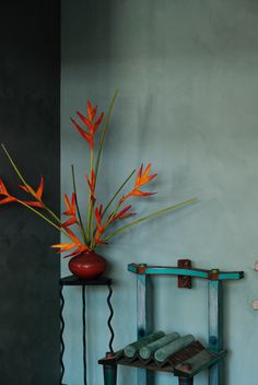 there is a vase with orange flowers in it on the table next to a shelf