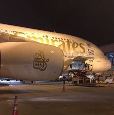 an airplane is parked on the tarmac at night with workers around it and other vehicles nearby