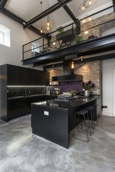 a kitchen with black cabinets and an island in the middle is lit by pendant lights