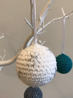 three crocheted balls hanging from a tree branch with white branches in the background