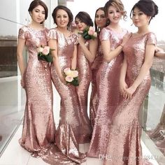 a group of women standing next to each other in front of a mirror wearing pink dresses