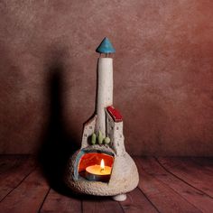 a small candle is lit in a clay pot on a wooden table next to a wall