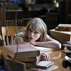 a woman sitting at a table with many books