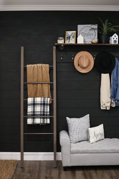 a living room with black walls and wooden flooring, a gray couch, two hats hanging on the wall