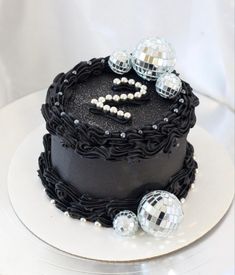 a black cake decorated with disco balls and beads