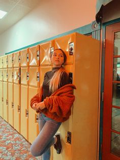 a woman leaning on a locker in a hallway