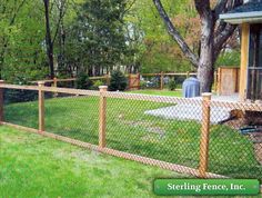 a fenced in area with grass and trees behind it, along with a blue sign that says sterling