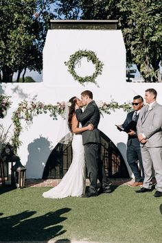 a bride and groom kissing in front of their wedding arch at the end of their ceremony