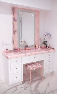 a white vanity with pink marble counter top and stool in front of the mirror on the wall