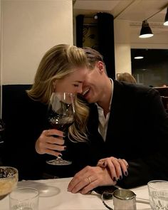 a man and woman sitting at a table with wine glasses