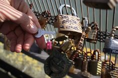 a person holding a key to a fence covered in padlocks with locks attached