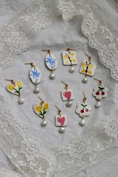 six pairs of earrings with flowers and hearts on them are sitting on a lace doily