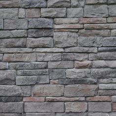 a stone wall made out of several different types of rocks, including gray and red