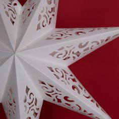 an origami star with intricate designs on it against a red background, cut out from paper