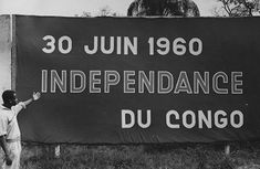 a man pointing to a sign that reads 30 june 1960 independence du conco