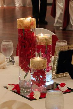 the centerpieces are decorated with red flowers and candles