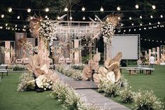 an outdoor wedding setup with white flowers and greenery on the grass, surrounded by string lights