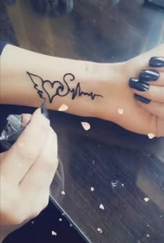 a woman is writing on her arm that has the word mom written in black ink