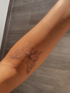 a woman's arm with a butterfly tattoo on the left side of her arm