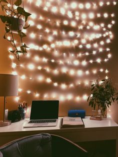 a laptop computer sitting on top of a desk next to a wall covered in lights