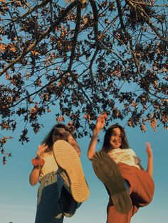 two girls jumping in the air under a tree