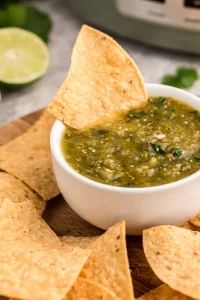 a white bowl filled with salsa and tortilla chips on top of a cutting board