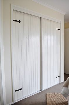 two white sliding doors with black handles in a room next to a couch and rug