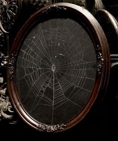 a spider web is shown in the center of a round mirror with ornate carvings around it