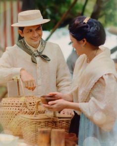 a man and woman standing next to each other in front of a table with baskets on it