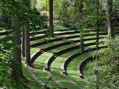 an outdoor seating area in the middle of a park with trees and grass on both sides