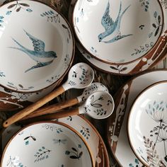 a table topped with lots of white plates and bowls filled with blue birds on them