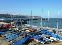 boats are lined up on the beach next to the water