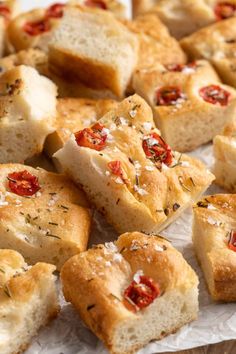 several pieces of bread with cheese and tomatoes on them sitting on top of wax paper