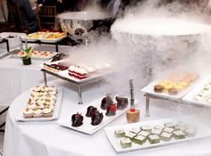 an assortment of desserts being served at a buffet table with steam rising from the top