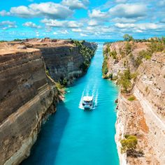 a boat traveling down a river next to a cliff