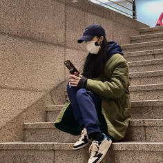 a man in a mask sitting on the steps looking at his cell phone