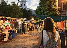 a woman is walking through an outdoor market