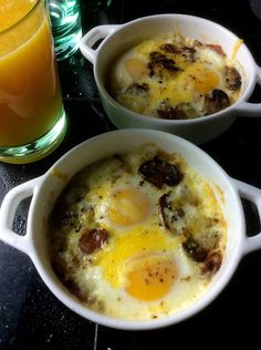 two white bowls filled with eggs on top of a table next to a glass of orange juice