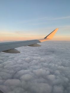 an airplane wing above the clouds at sunset